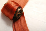 Close-up of copper hair extensions on a model, showing long, wavy texture